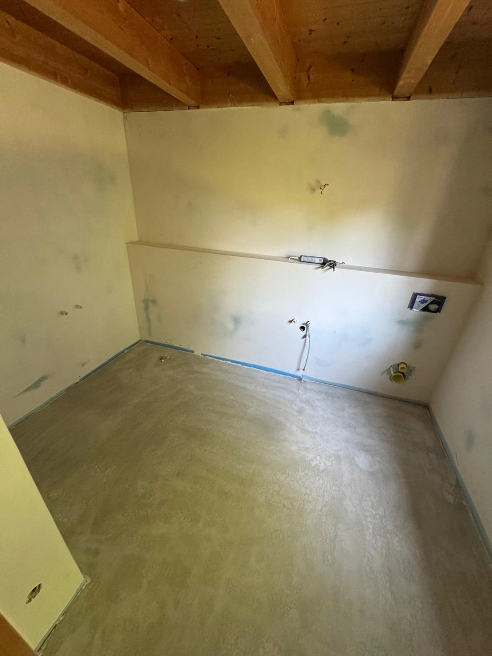 Unfertiger Badezimmerboden mit Estrich und roher Sanitärinstallation für Fliesenarbeiten