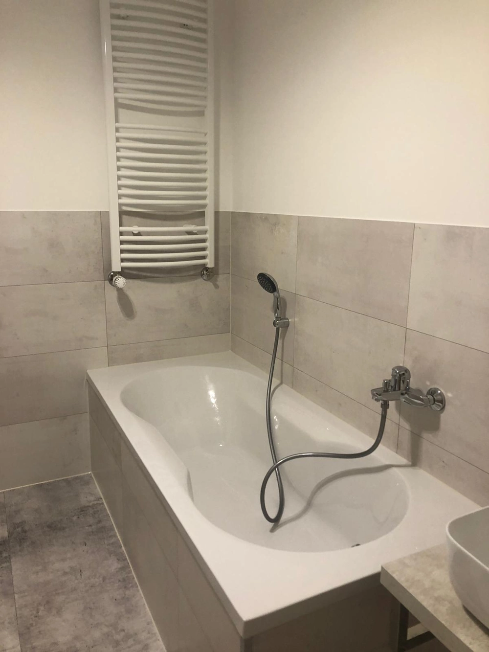 Gefliestes Badezimmer mit Badewanne, Handbrause und Armatur – Fliesenarbeiten